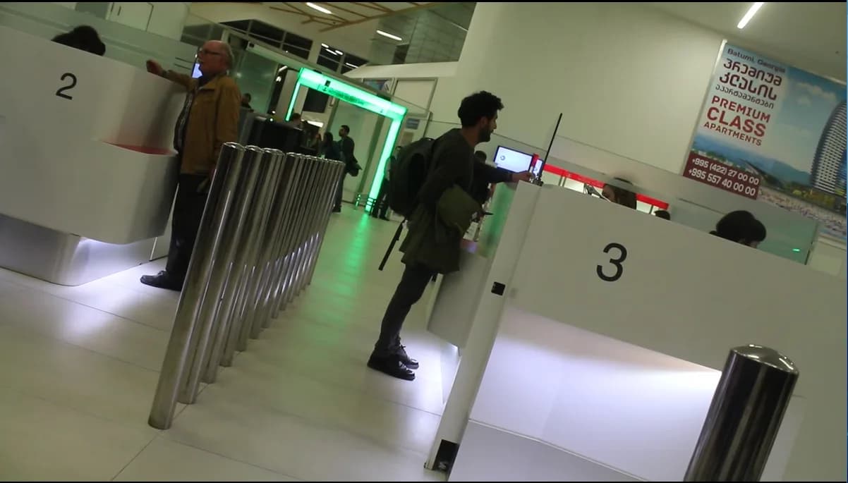 Passport control at Kutaisi International Airport: numbered booths and a stanchion queue leading through to the gates